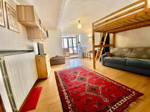 un soggiorno con divano e tappeto rosso di Monolocale accogliente a Bardonecchia