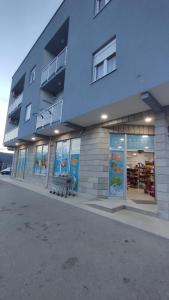 a building with a bench in front of a store at Apartman Ena in Bileća