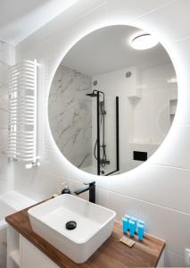 a bathroom with a white sink and a mirror at Brzeziny Deluxe Apartment in Warsaw