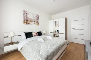 a white bedroom with a bed with two towels on it at Brzeziny Deluxe Apartment in Warsaw
