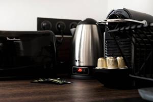 a desk with a coffee maker and a clock on it at Pur bonheur Hôtel de ville - clim et balnéo AIL in Lyon +22 photos
