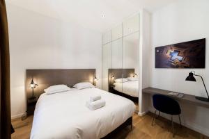 a bedroom with a white bed and a desk and a mirror at Pure happiness -AC and balneotherapy AIL in Lyon