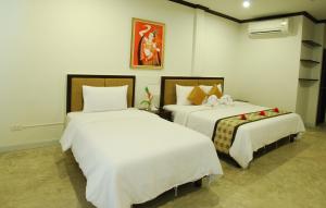 um quarto com 2 camas e lençóis brancos em Phukamala Suite em Praia de Kamala