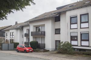 um carro vermelho estacionado em frente a um edifício em Hackeschladenweg 15 - Winterberg 'Auszeit Winterberg' em Winterberg