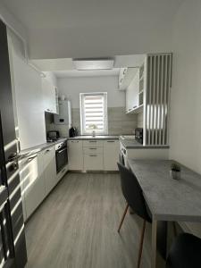 a kitchen with white cabinets and a table and a window at Cozy Holidays in Center of Suceava Esplanada in Suceava