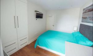 a white bedroom with a blue bed and white cabinets at Splendid Euston flat in London