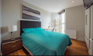 a bedroom with a large bed with a blue blanket at Splendid Euston flat in London