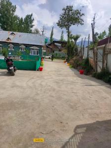 a dirt road with a motorcycle parked in front of a building at Habib Guest House (Gulmarg) in Gulmarg