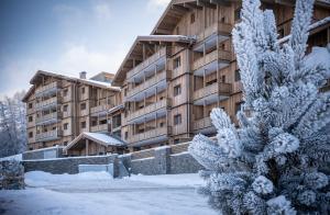 a building in the snow with a snow covered tree at Snoroc by Daddy Pool- TERRESENS in Aime-La Plagne