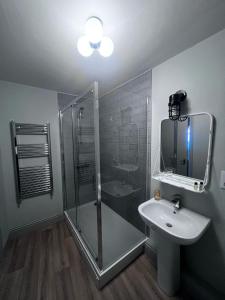uma casa de banho com uma cabina de duche em vidro e um lavatório. em The Victorian Tap em Hexham