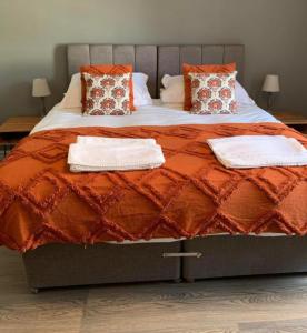 uma cama grande com almofadas cor-de-laranja e brancas em The Victorian Tap em Hexham