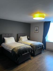 a bedroom with two beds and a large window at The Victorian Tap in Hexham