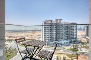 un balcón con 2 bancos, una mesa y una ciudad en Azizi Riviera Small Family Private Apartment Dubai, en Dubái