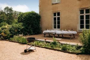 Cré-sur-Loir的住宿－Château de Marigné - Gîte de charme- 15 pl，一座花园,在一座建筑前设有桌子和烧烤架