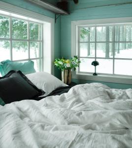 a bed in a bedroom with two windows at Cabin by Byske river surrounded by the forest in Byske