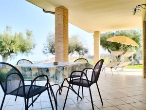 stół z krzesłami i parasol na patio w obiekcie Residenza Armonia w mieście Roseto degli Abruzzi
