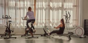 2 femmes faisant de l'exercice sur des vélos d'exercice dans une salle de sport dans l'établissement Villages Clubs du Soleil - OZ EN OISANS, à Oz