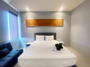 um quarto com uma cama branca e um sofá azul em Swiss-Belexpress Rest Area KM 164, Cipali em Majalengka