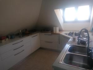 uma cozinha com armários brancos, um lavatório e uma janela em Coros em Nuoro
