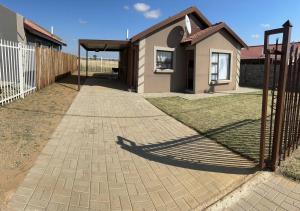 um passadiço de tijolos que leva a uma casa com uma cerca em MV self-catering Linden em Bloemfontein