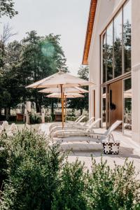 een patio met een parasol, stoelen en tafels bij Der Eisvogel - Wellness- & Genusshotel in Bad Gögging