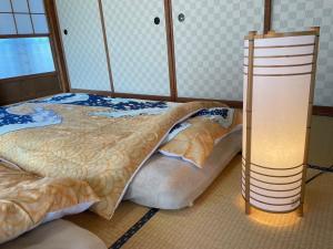 Nishiwada的住宿－農家古民家ねこざえもん奥屋敷 Nekozaemon-Gest house，一间卧室配有一张床,旁边配有一盏灯