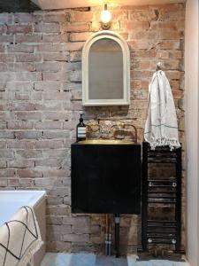 a bathroom with a sink and a brick wall at Stylish 1 bed with large plant filled garden in London