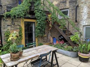 a wooden table in front of a building with plants at Stylish 1 bed with large plant filled garden in London