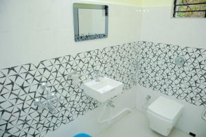 ein Badezimmer mit Waschbecken, Toilette und Spiegel in der Unterkunft Ichhepuron in Shānti Niketan