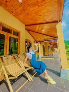 a woman in a blue dress standing next to a chair at Sky Bay Ha Giang in Ha Giang