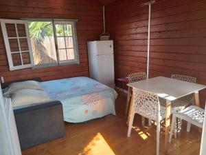 Zimmer mit einem Bett, einem Tisch und einem Kühlschrank in der Unterkunft Bungalow des papayes in Saint-Louis