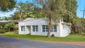 a white house with a tree in front of it at Family Pearl - Pearl Beach in Pearl Beach