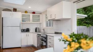 a kitchen with white cabinets and a white refrigerator at Family Pearl - Pearl Beach in Pearl Beach