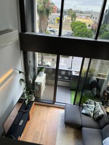 a living room with a couch and a large window at Centrally Located Modern Loft w Free Parking, Infinity Pool, Workspace in Melbourne