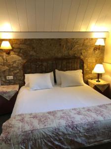 a bedroom with a large white bed with two lamps at Hotel Xalet la Coromina in Viladrau