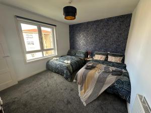 a bedroom with two beds and a window at Glasgow Modern style home , separate entrance in Knightswood