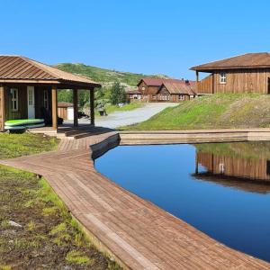 a wooden bridge over a pond in front of a house at Korgfjellet Fjellstue as in Korgen