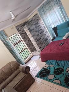 uma sala de estar com um sofá, uma cama e janelas em COMFORT ZONE GUEST HOUSE em Zeerust