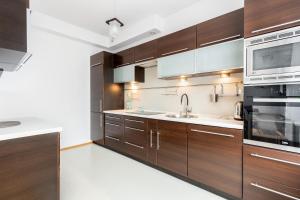 a kitchen with wooden cabinets and a sink and a microwave at Borkowska Comfort Apartment in Krakow