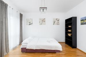 a white bedroom with a bed and a black cabinet at Borkowska Comfort Apartment in Krakow