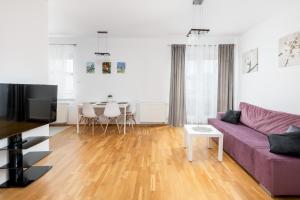 sala de estar con sofá púrpura y mesa en Borkowska Comfort Apartment en Cracovia