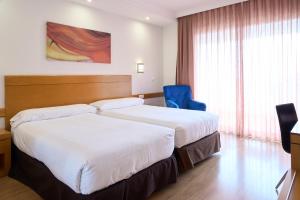 Cette chambre d'hôtel comprend deux lits et une chaise bleue. dans l'établissement Hotel Maya Alicante, à Alicante