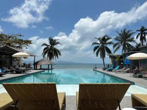 a swimming pool with chairs and palm trees and the ocean at The Sea Resort Haad Rin in Haad Rin