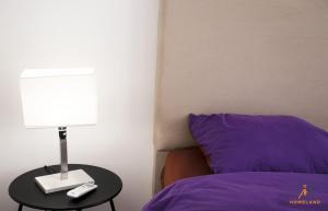 a bed with a purple pillow and a table with a lamp at pool house in Douar ech Chott