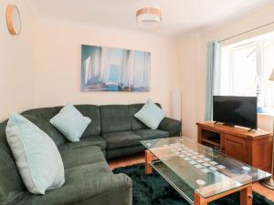 a living room with a green couch and a television at Garland in Weymouth