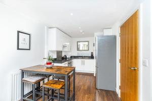 a kitchen with a table and chairs and a refrigerator at Stunning 1BR Flat w/Balcony, 2min to Woolwich Tube in London