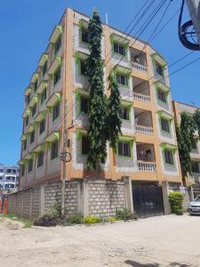 een hoog gebouw met een boom ervoor bij The Sunset Home's in Mombasa