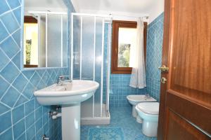 bagno piastrellato blu con lavandino e servizi igienici di Residence Rena Majore a Rena Majore