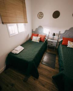 a bedroom with two green beds and a table at Casa Rural VUT El Rincón de Eulogio in El Torno