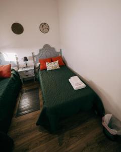 1 dormitorio con 1 cama con sábanas verdes y almohadas de color naranja en Casa Rural VUT El Rincón de Eulogio, en El Torno
